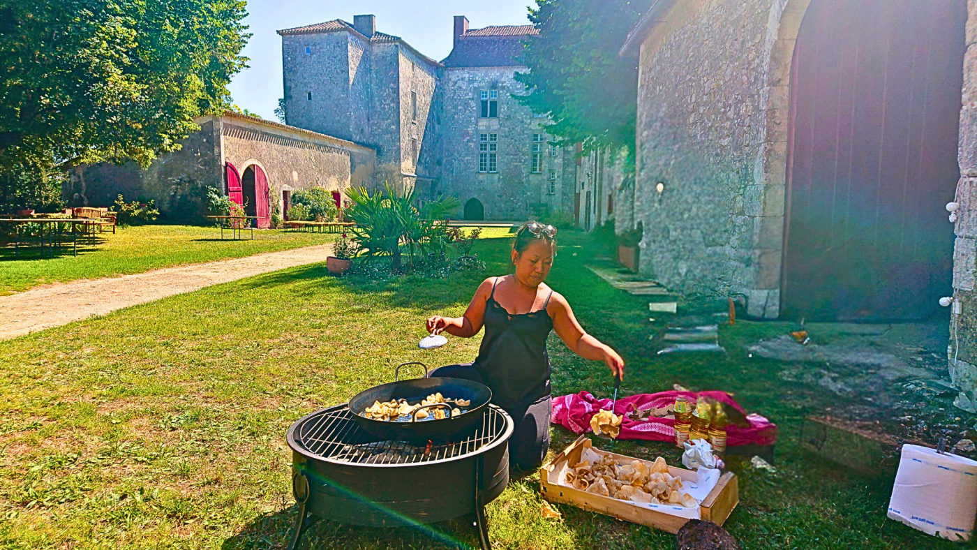 Chef Novy frying prawn crackers over a fire pit in the courtyard of a historic French château